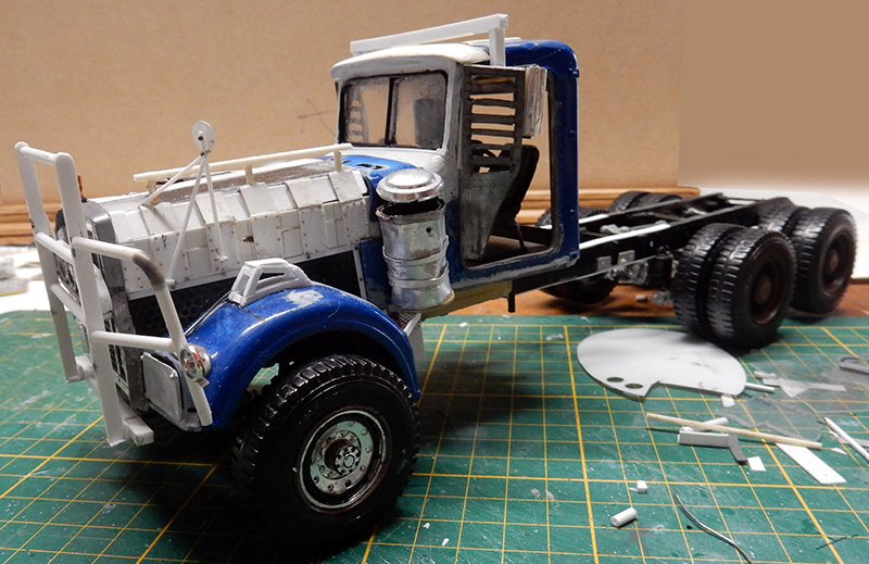 Maquette de dépanneuse bleue et blanche en cours de montage sur tapis de découpe