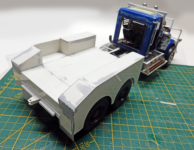 Maquette de dépanneuse en construction, plateau arrière blanc et cabine bleue sur tapis de découpe