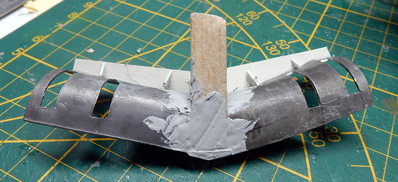 Pièce de maquette en construction avec mastic et tige bois sur tapis de découpe vert