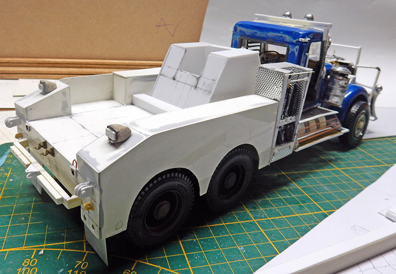 Maquette de dépanneuse avec cabine bleue et plateau arrière blanc en construction sur tapis de découpe