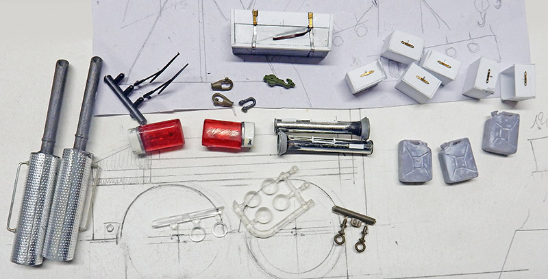 Pièces détaillées de maquette dépanneuse posées sur un plan : jerricans, feux rouges et accessoires métalliques