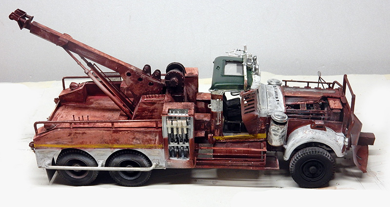 Maquette de dépanneuse rouillée avec grue de levage et cabine verte, vue de profil