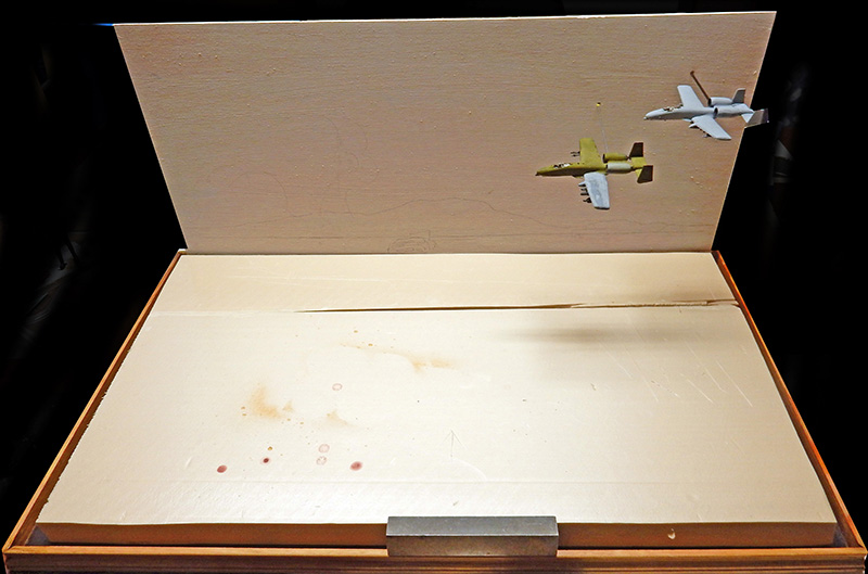 Diorama en bois avec deux maquettes d'avions fixées sur le panneau vertical