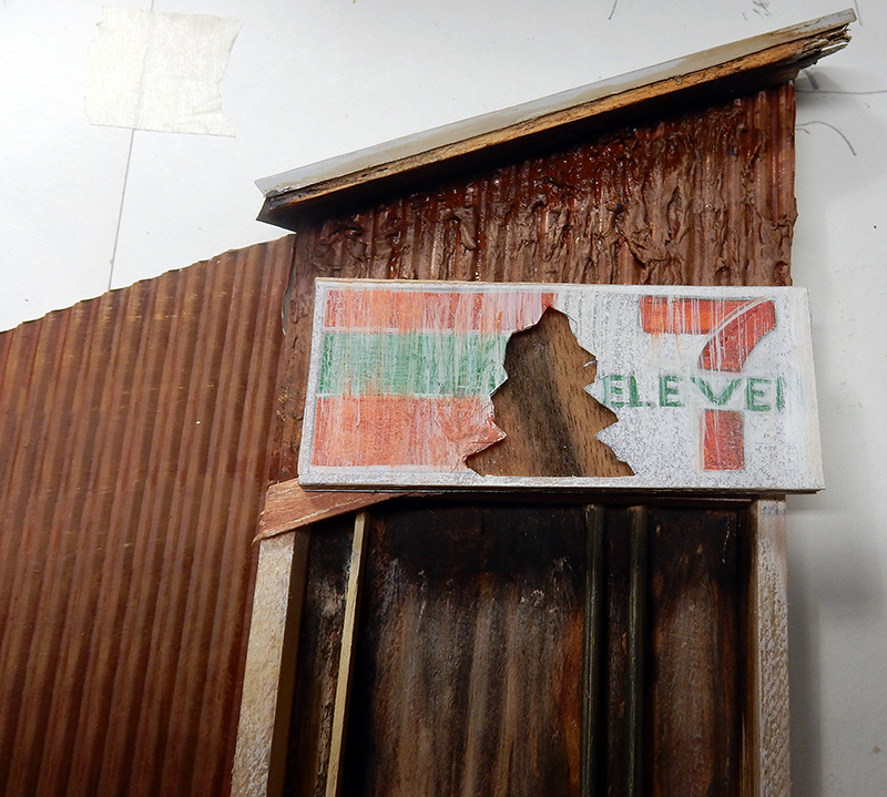 Décor de bâtiment en bois patiné avec enseigne 7-Eleven vieillie et tôle ondulée rouillée