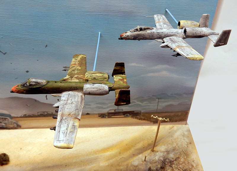 Deux maquettes d'avions A-10 camouflés en vol au-dessus d'un diorama désertique peint