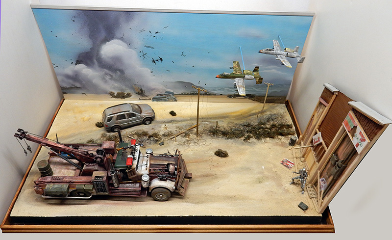 Diorama de dépanneuse rouillée dans un désert avec avions de chasse et explosion en arrière-plan