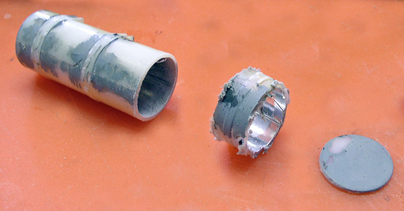 Pièces cylindriques de maquette en plastique gris masticées et un disque sur fond orange