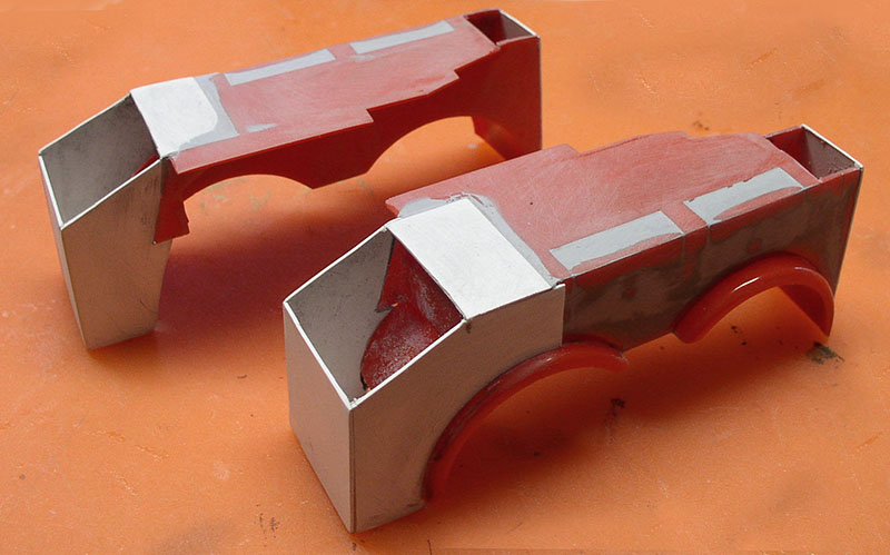 Deux maquettes en carton de carrosserie de dépanneuse peintes en rouge et argent sur fond orange