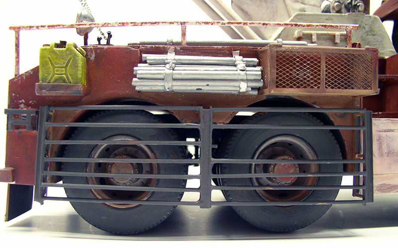 Vue latérale de la maquette de dépanneuse rouillée avec roues arrière, jerrican jaune et tubes métalliques
