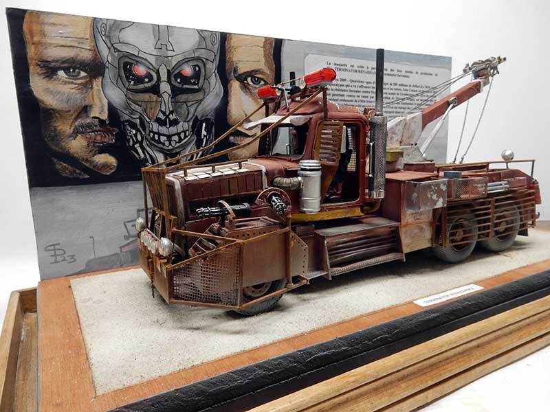 Maquette de dépanneuse rouillée Terminator Renaissance devant décor peint de crâne robotique et visages