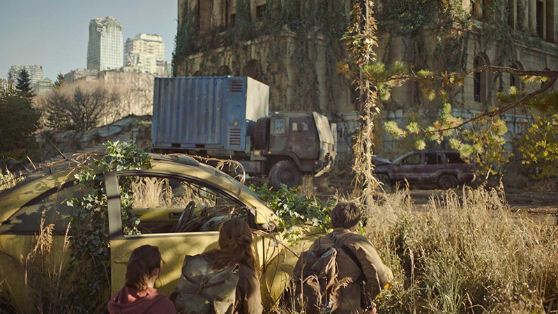 Diorama post-apocalyptique de The Last of Us 2 avec personnages cachés derrière une voiture rouillée envahie par la végétation
