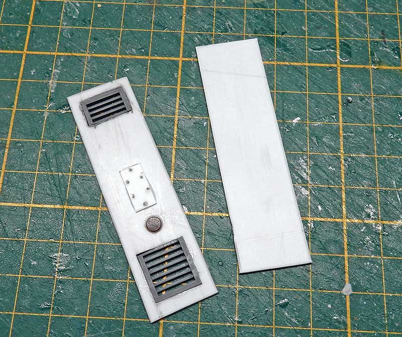 Pièces de maquette en plasticard avec grilles de ventilation et détails, sur tapis de découpe vert
