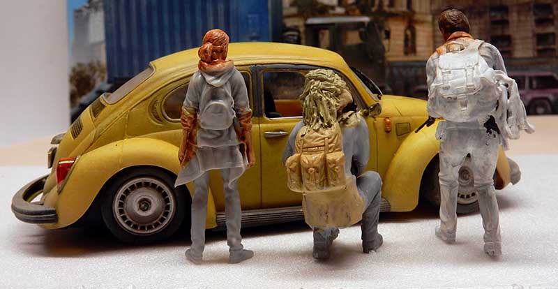 Diorama de maquette avec trois figurines à sac à dos près d'une Coccinelle Volkswagen jaune