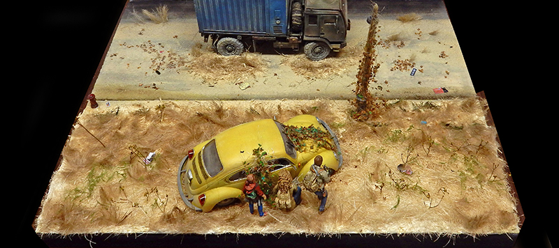 Diorama post-apocalyptique avec voiture jaune abandonnée, camion et figurines de survivants dans un paysage désolé