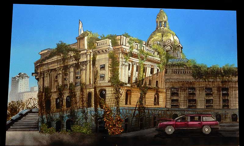 Maquette d'un bâtiment monumental à dôme envahi par la végétation avec voiture rouge abandonnée