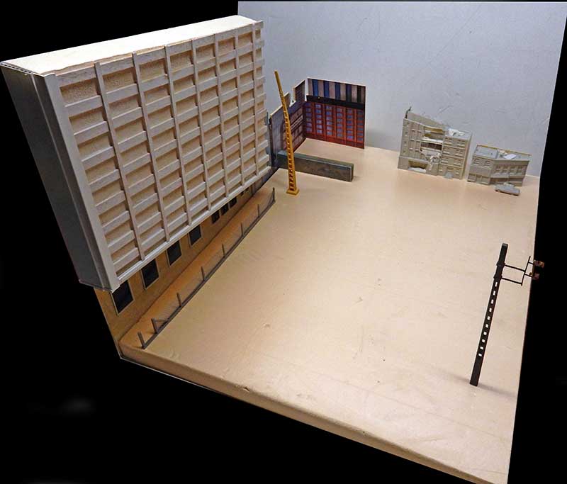 Maquette en construction d'un décor urbain avec immeuble, échelle jaune et bâtiments inspirés de The Last of Us