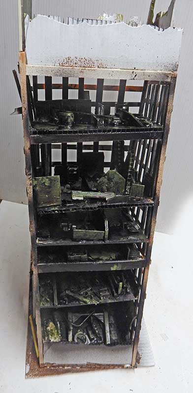 Maquette d'immeuble en ruine sur plusieurs étages aux structures noircies et envahies par la végétation