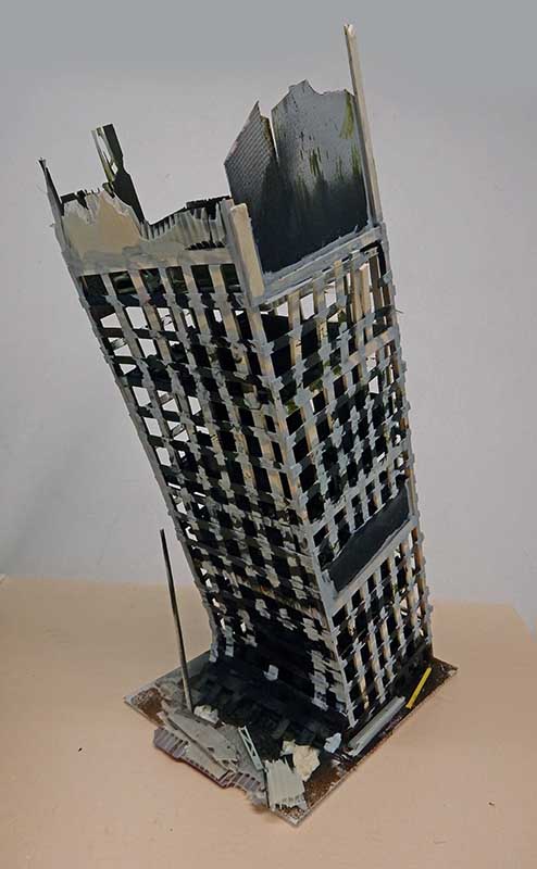 Maquette d'immeuble en ruine penché aux étages éventrés sur socle, ambiance post-apocalyptique