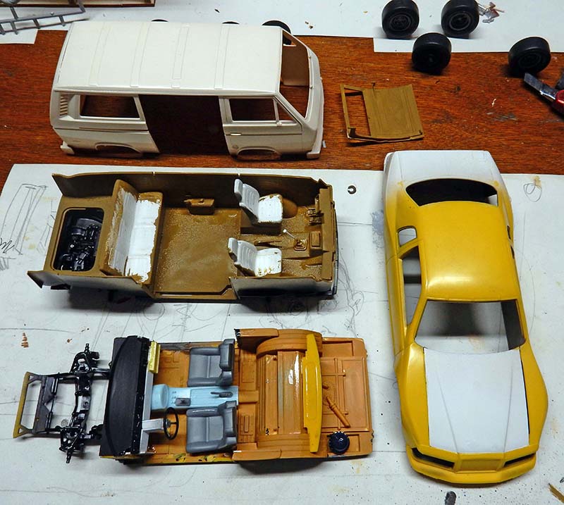 Maquettes de véhicules en cours d'assemblage, fourgon, intérieurs et voiture jaune sur table de modélisme