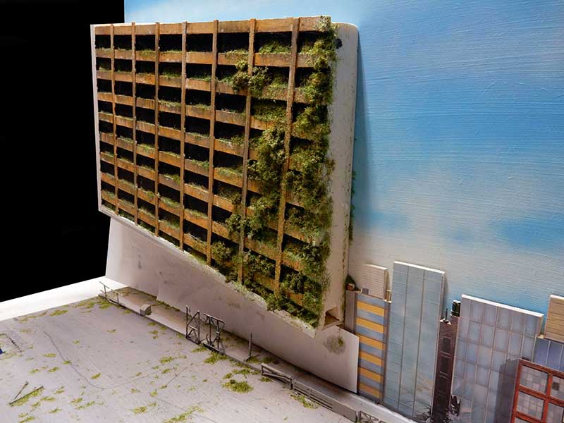 Maquette d'immeuble en ruine envahi par la végétation devant un ciel bleu, ambiance The Last of Us