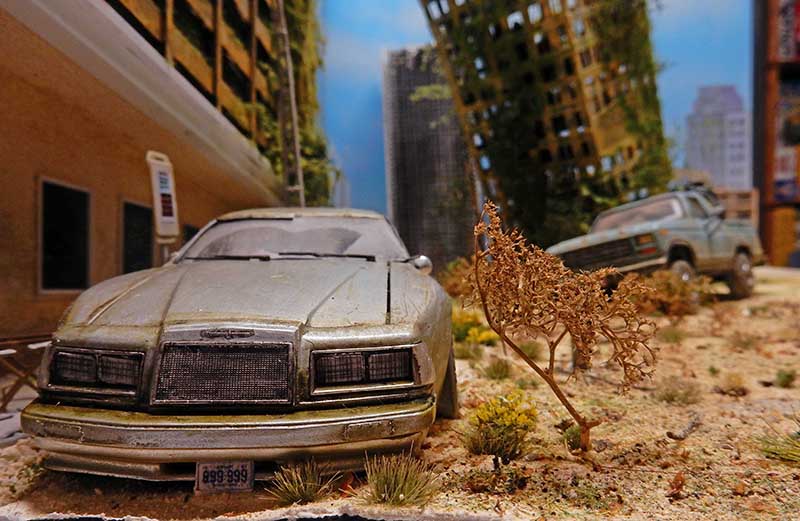 Diorama de voiture abandonnée et rouillée dans une ville en ruines envahie par la végétation