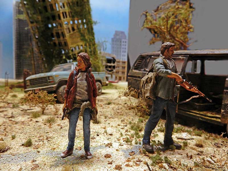 Figurines de Joel et Ellie dans un diorama urbain en ruines avec véhicules abandonnés