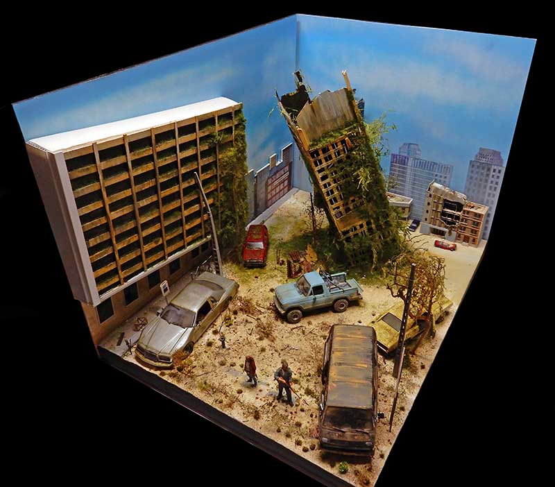 Diorama de ville post-apocalyptique avec immeubles en ruine, voitures abandonnées et figurines de survivants