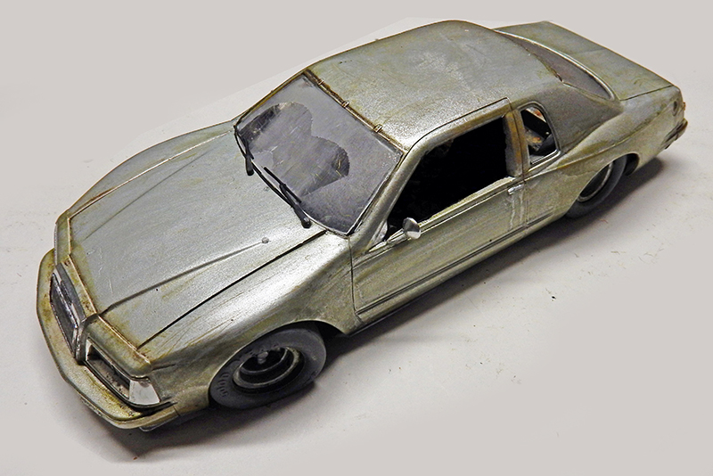 Maquette de voiture berline abandonnée et vieillie, vitres cassées, ambiance post-apocalyptique The Last of Us