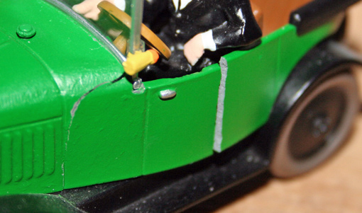 Maquette d'une voiture ancienne verte avec figurine au volant, vue rapprochée du capot