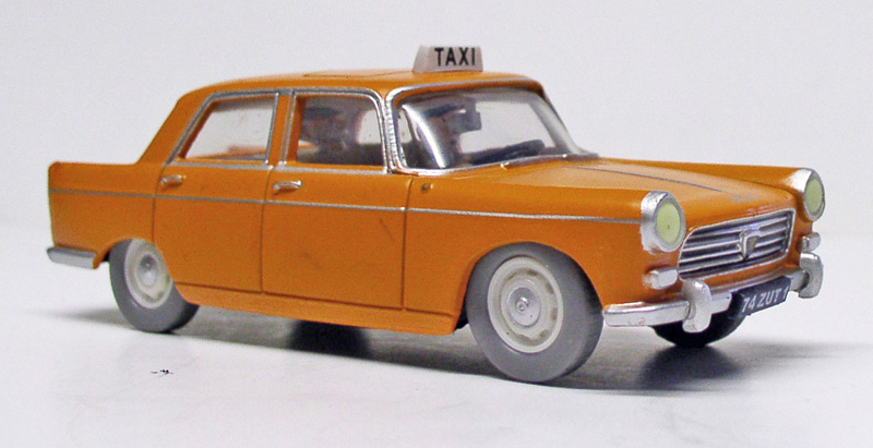 Maquette miniature d'une Peugeot 404 taxi orange avec enseigne TAXI sur le toit