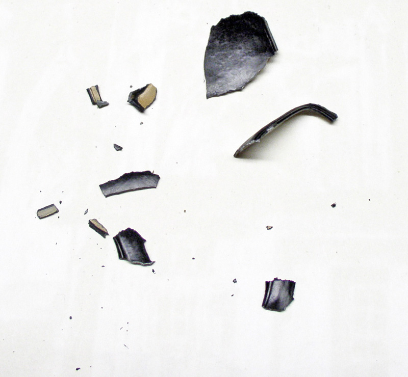 Fragments de pièce miniature noire cassée éparpillés sur un fond blanc