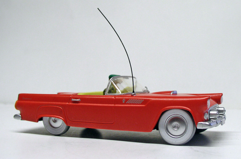 Maquette de cabriolet rouge décapotable avec longue antenne, vue de profil sur fond gris