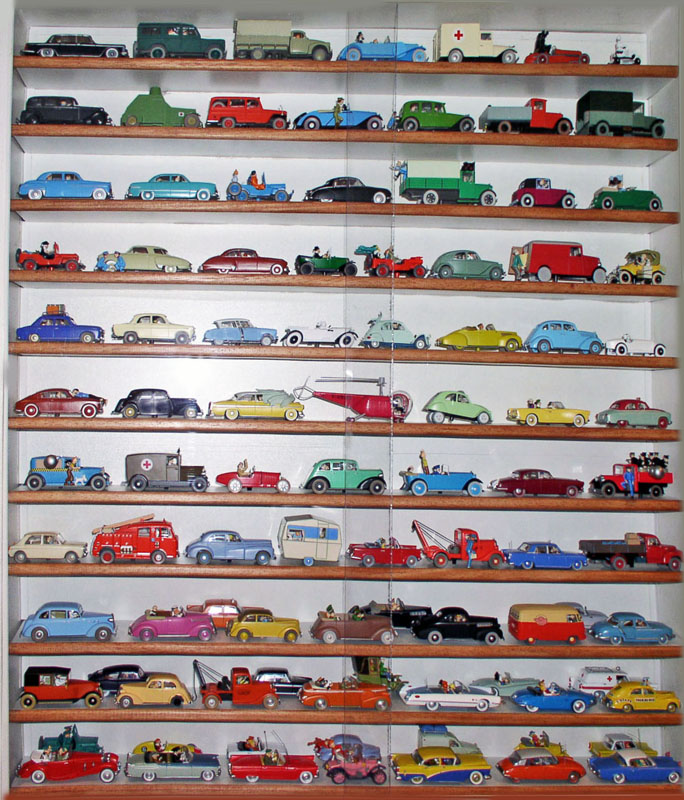 Vitrine murale présentant une collection de voitures miniatures Tintin et Spirou alignées sur étagères