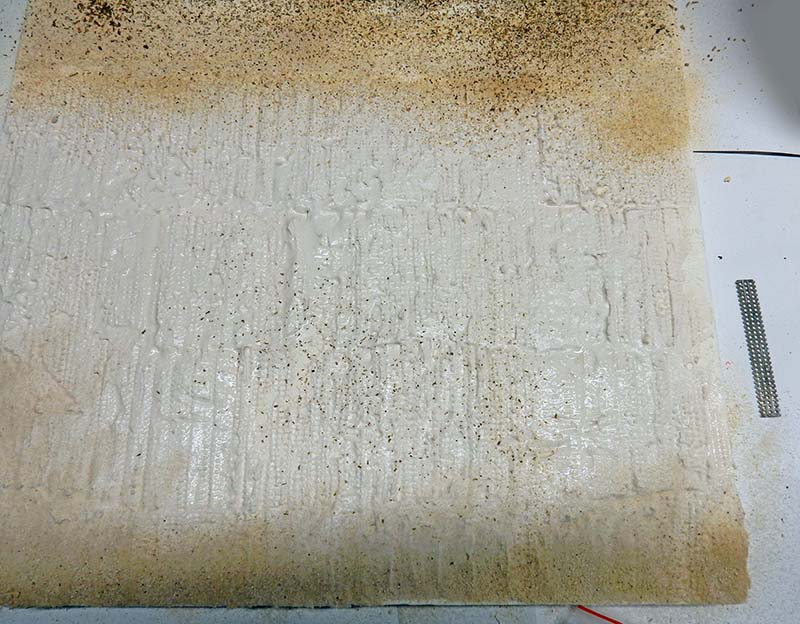 Surface de socle en plâtre texturée pour diorama, teintée d'ocre et mouchetée de pigments