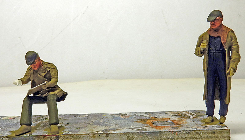 Deux figurines d'ouvriers peintes à l'échelle 1/24, l'un assis lisant, l'autre debout