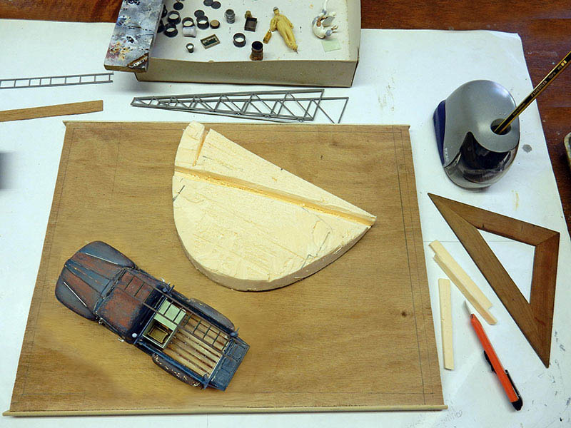 Maquette de voiture vieillie posée sur un socle bois avec décor en mousse et outils de modélisme
