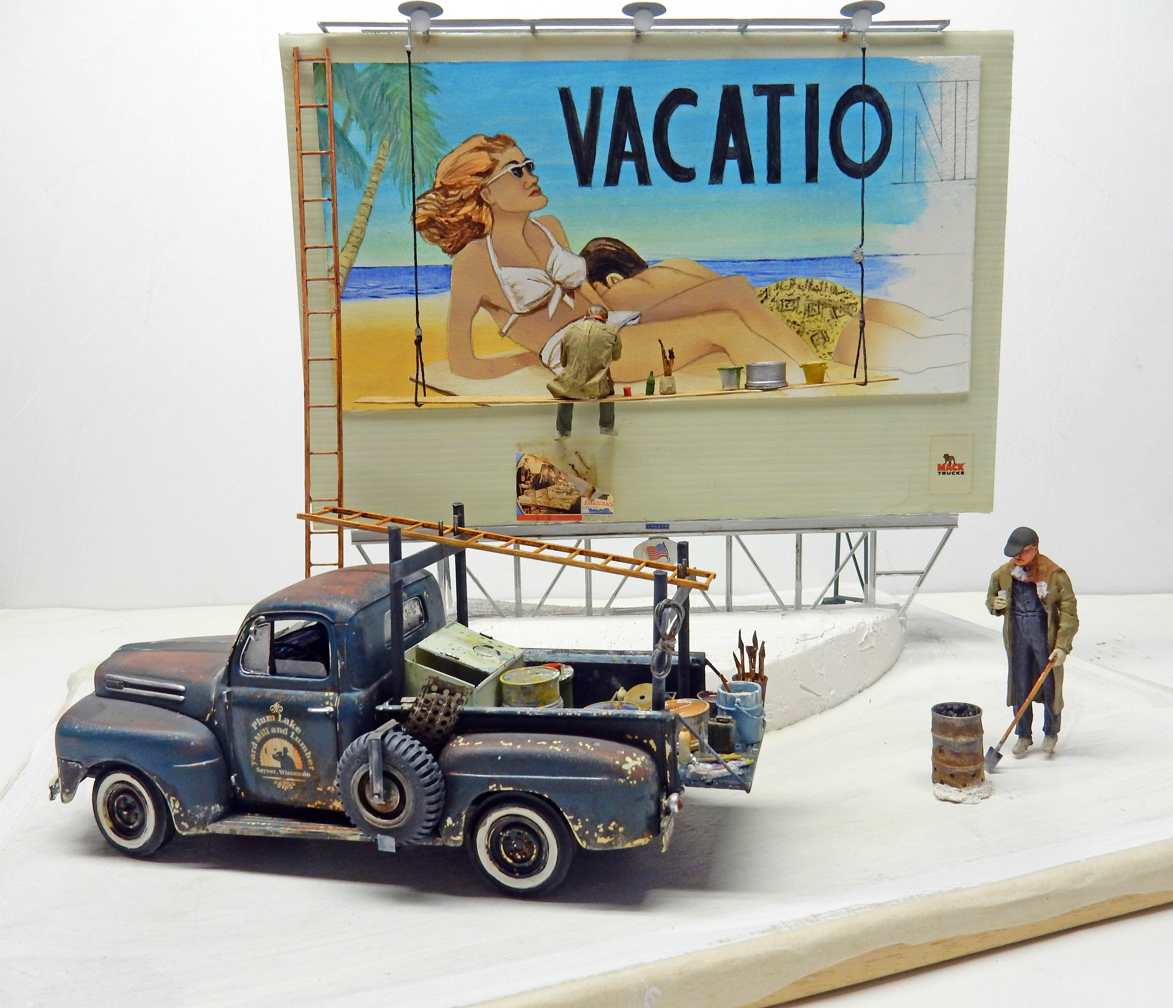 Diorama avec pick-up bleu vieilli et figurine devant un panneau publicitaire « Vacation » peint