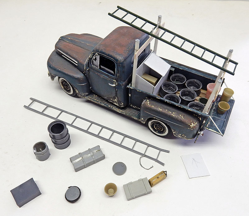 Maquette de pick-up vieilli avec échelles, fûts et caisses d'accessoires posés autour