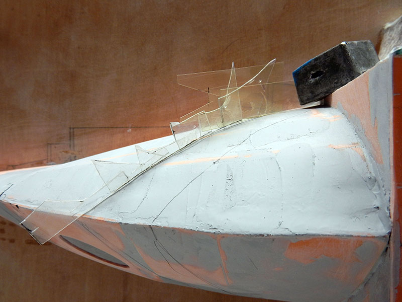 Gabarits en plastique transparent positionnés sur la coque mastiquée de l'astronef en construction