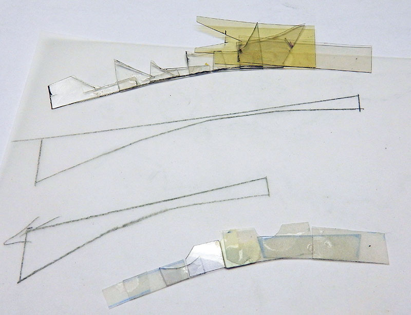 Découpes en plastique transparent et ambré posées sur un plan crayonné de l'astronef