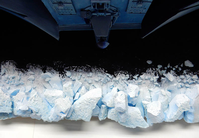 Dessous de l'astronef bleu survolant un champ de blocs de glace fracturés