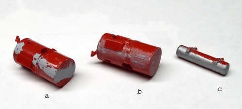 Trois réservoirs de maquette peints en rouge montrant l'effet d'écaillage et de vieillissement du métal