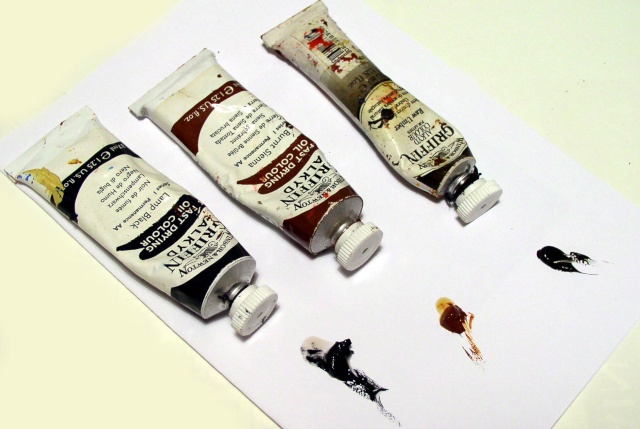 Trois tubes de peinture à l'huile avec touches de couleur déposées sur une feuille blanche