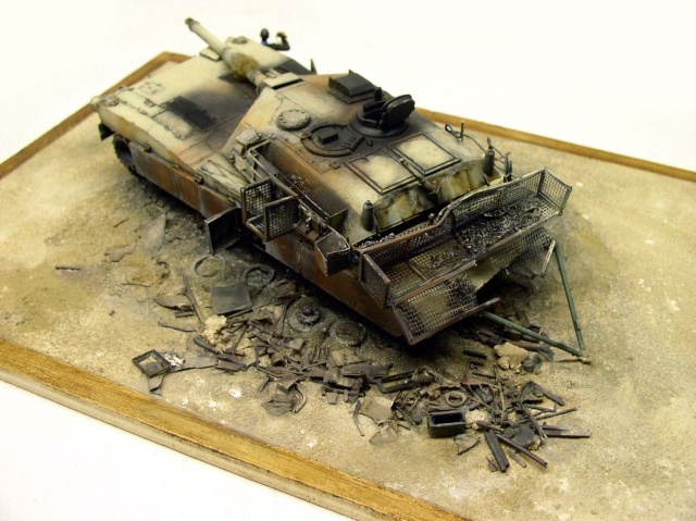 Maquette de char Abrams vieilli sur diorama de ruines avec paniers grillagés latéraux