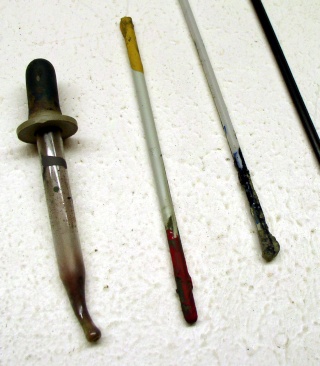 Pipette compte-gouttes et pinceaux usagés tachés de peinture posés sur une surface blanche