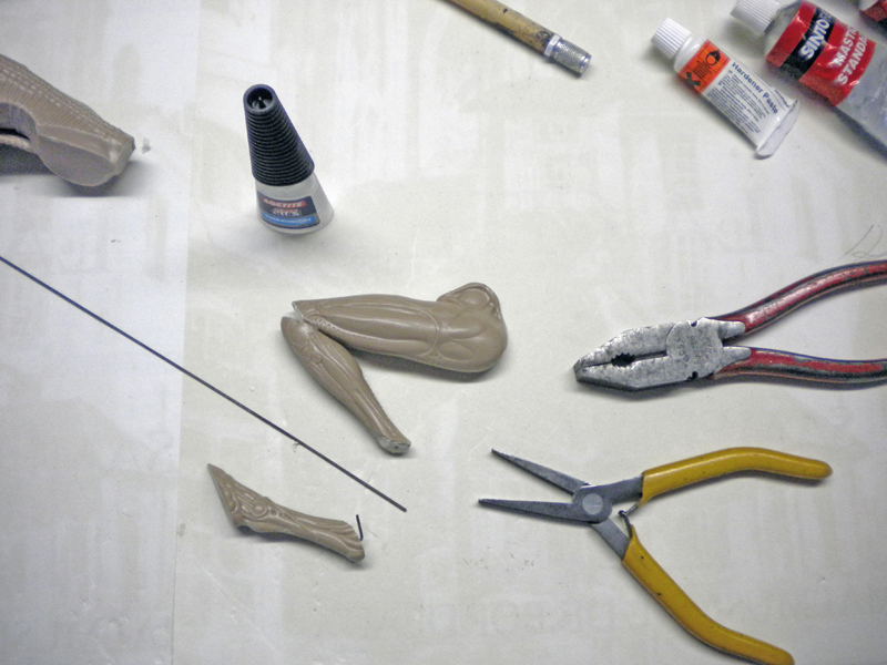 Pièces de maquette de la créature Alien 3 avec colle, pinces et fil métallique sur établi