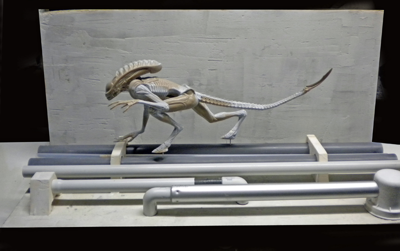 Maquette du xénomorphe quadrupède d'Alien 3 en position de course sur un décor industriel gris