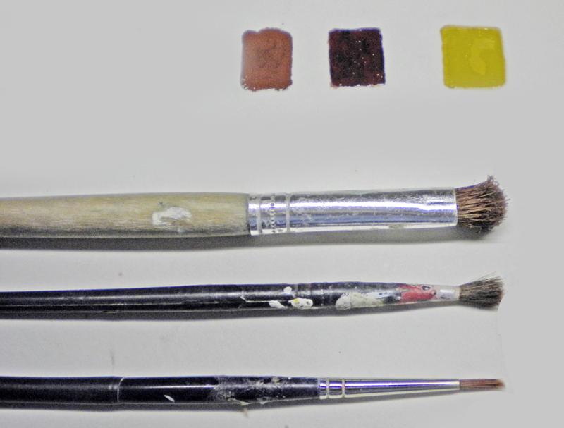 Trois pinceaux de tailles différentes et échantillons de peinture marron et jaune pour maquette Alien 3