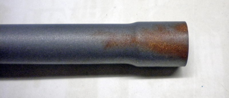 Tube métallique gris peint avec effet de rouille orangée vieillie près de l'extrémité