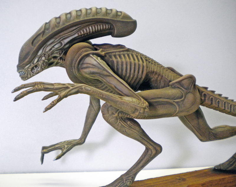 Maquette peinte du xénomorphe d'Alien 3 accroupi, tons brun-vert, posée sur socle bois